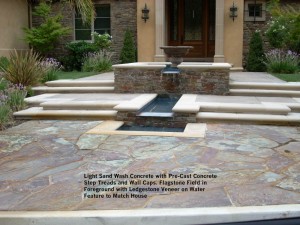 Light Sand Wash Concrete with Pre-Cast Concrete Step Treads and Wall Caps. Flagstone Field in Foreground with Ledgestone Veneer on Water Feature to Match House