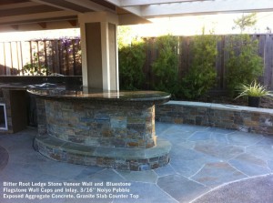 Bitter Root Ledge Stone Veneer Wall and  Bluestone Flagstone Wall Caps and Inlay. 3_16” Noiyo Pebble Exposed Aggregate Concrete. Granite Slab Counter Top